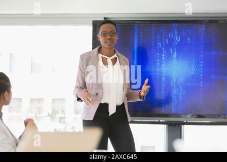 Donna d'affari nella sala conferenze con schermo televisivo Foto Stock