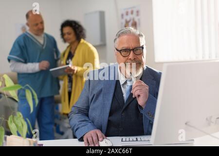 Ritratto medico sicuro maschio che lavora al computer in ufficio medici Foto Stock