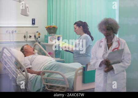 I medici facendo turni, parlando con il paziente nella stanza di ospedale Foto Stock