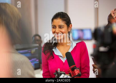 Sorridente, fiducioso femminile comunità studente di giornalismo college dietro microfono Foto Stock