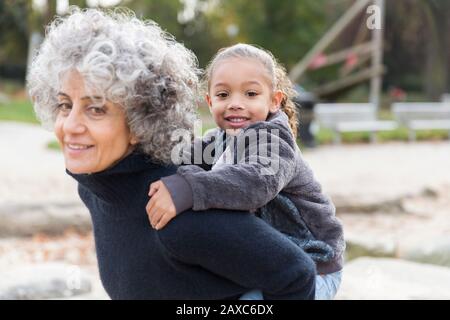 Ritratto nonna sorridente piggybacking nipote Foto Stock