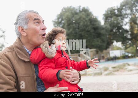 Nonno e nipote del bambino che giocano con le bolle nel parco Foto Stock