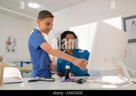 Paziente pediatra e bambino femminile che usa il computer in ufficio medico Foto Stock