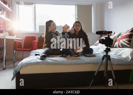 Adolescenti ragazze vlogging, dimostrando applicazione di trucco sul letto Foto Stock
