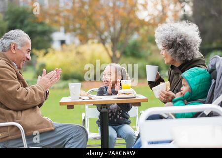 Nonni e nipoti che gustano il pranzo al tavolo del parco Foto Stock