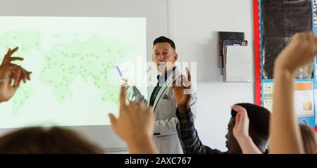 Insegnante di scuola superiore maschile che conduce la lezione sullo schermo di proiezione in classe Foto Stock