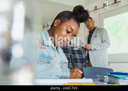 Studentessa di scuola superiore focalizzata che studia in classe Foto Stock