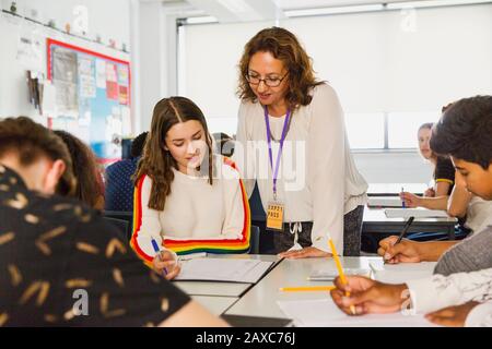 Insegnante femminile di scuola superiore che aiuta la ragazza studente a studiare a tavola in classe Foto Stock