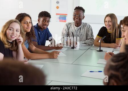 Sorridendo gli studenti delle scuole superiori che ascoltano in classe di dibattito Foto Stock