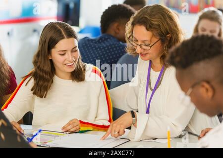 Insegnante femminile di scuola superiore che aiuta la ragazza studente con i compiti a casa in classe Foto Stock