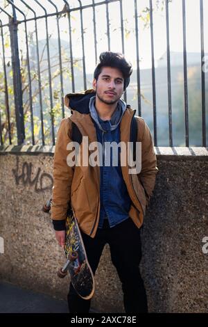 Ritratto sicuro giovane uomo che tiene skateboard Foto Stock