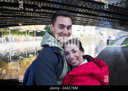 Ritratto felice giovane coppia abbracciando lungo il canale Foto Stock