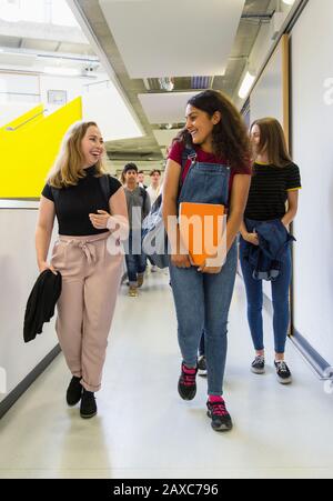 Studenti di ragazze giovani che camminano e parlano in corridoio Foto Stock