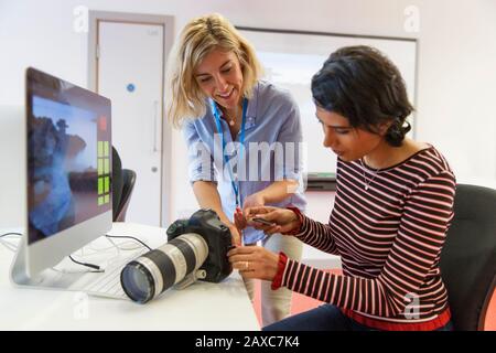 Fotografo femminile che insegna allo studente come utilizzare la fotocamera SLR Foto Stock