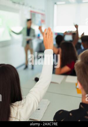 High School ragazza studente che alza la mano, facendo domande durante la lezione in classe Foto Stock