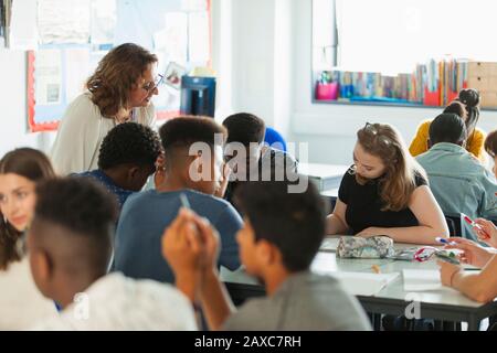 Insegnante di scuola superiore che aiuta gli studenti a studiare in classe Foto Stock