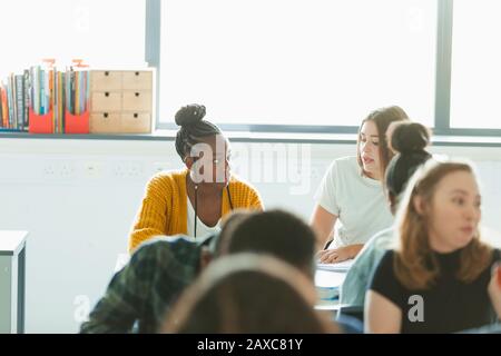 Gli studenti delle ragazze della scuola superiore che parlano, facendo i compiti in classe Foto Stock