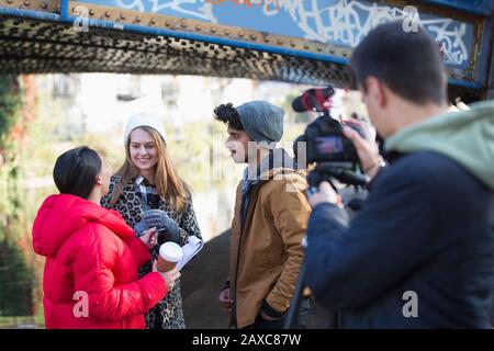 Giovani studenti di film filmando sotto ponte urbano Foto Stock