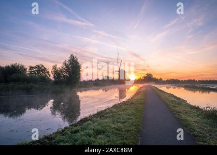 Splendida immagine paesaggistica con mulino a vento tradizionale olandese e bassa nebbia all'alba Foto Stock