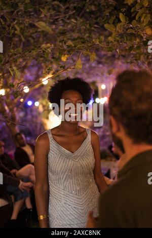 Felice giovane donna che parla con l'uomo a festa giardino Foto Stock