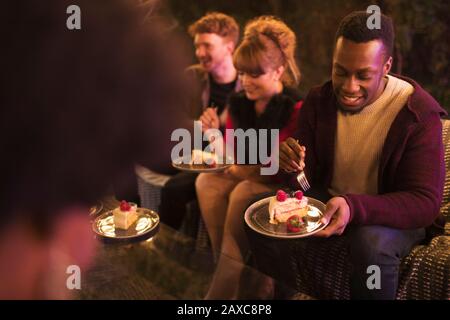 Gli amici festeggiano il compleanno, mangiando la torta sul patio Foto Stock