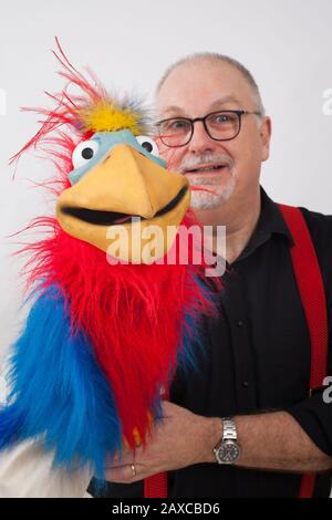 Un ventriloquista con un pappagallo sul suo braccio Foto Stock