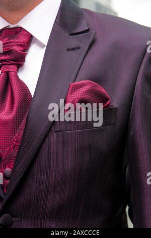 Traje de novio granate con caleco bordado y corbatón. Foto Stock