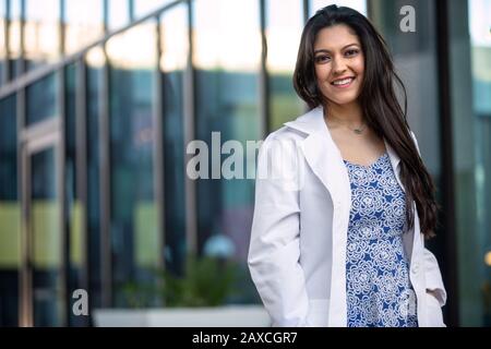 Medico professionista multietnico femminile in un camice bianco che si alza dal lato della pratica privata, possibilmente medico, igienista dentale, terapeuta, psicia Foto Stock