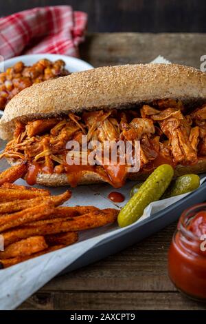 Cric-frutta vegan barbecue su pane di hoagie di grano intero. Fagioli cotti in stile meridionale, patatine fritte e insalata di cavolo. Foto Stock