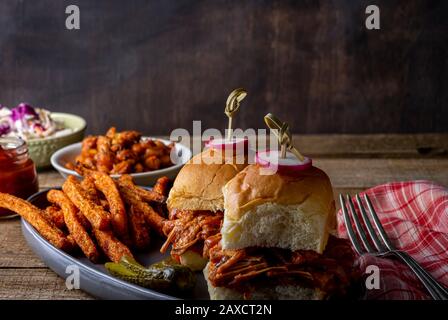 Cursori grigliati vegani con frutta e jack, con fagioli cotti al barbecue, patatine fritte e insalata di cavolo cotte al forno. Foto Stock