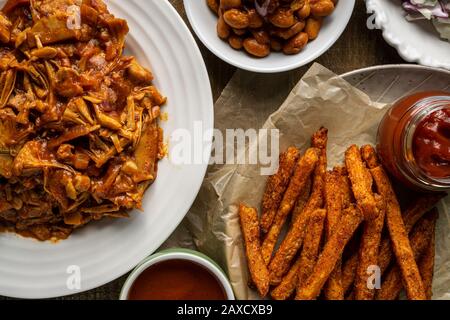 Piatto grigliato vegano. Jack-frutta alla griglia, fagioli al forno in stile meridionale, insalata di cavolo, panini per la cena e patatine fritte dolci. Foto Stock