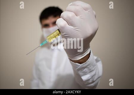 Una siringa tenuta in mano. Contiene liquido giallo. Foto Stock