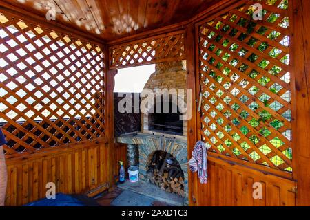 Stufa in pietra con legno in un gazebo in legno per il relax. Gazebo per barbecue. Foto Stock