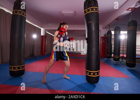 Kickboxer ragazza che lavora con la borsa pesante, pugni e calci Foto Stock