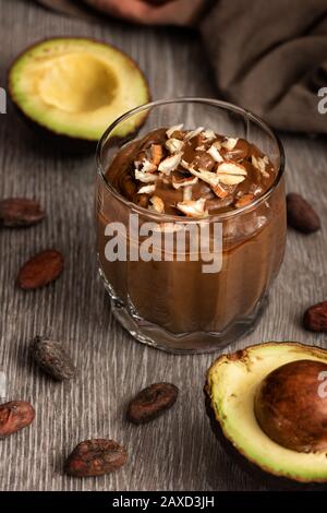 Dessert avocado con cacao in un bicchiere su una superficie di legno. Prodotti vegani crudi. Foto Stock