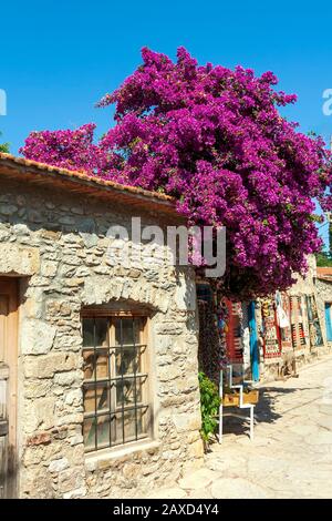 Casa in pietra con fiori nella città vecchia di Datca resort. Anche alcuni tappeti appesi alle pareti Foto Stock