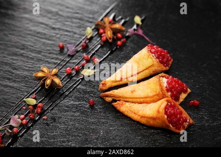 Pate di coniglio in corni croccanti decorato con spezie su un piatto di pietra nera Foto Stock