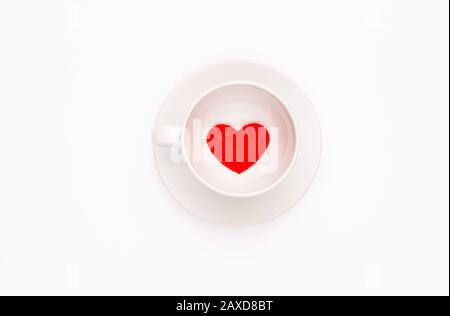 Vista dall'alto di una tazza di caffè bianca con un cuore su sfondo bianco. Biglietto d'auguri per San Valentino. Foto Stock