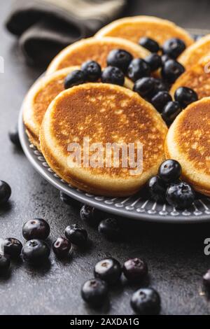 Dolci frittelle fatte in casa e mirtilli sul vecchio tavolo da cucina. Foto Stock