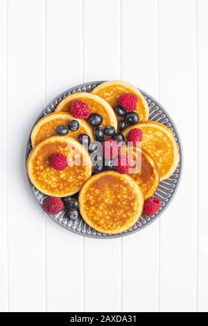 Dolci frittelle fatte in casa con mirtilli e lamponi su piastra. Vista dall'alto. Foto Stock