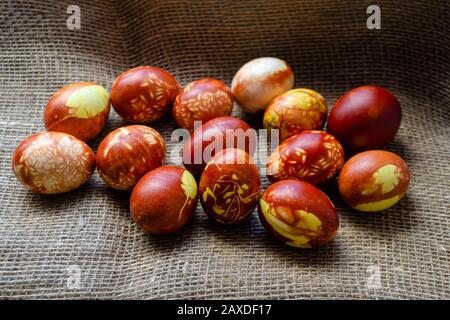 Uova di pollo colorate con metodo naturale oldfasato da buccia di cipolla. Uova marroni con diversi motivi naturali sul burlap beige. Messa a fuoco selettiva con Foto Stock