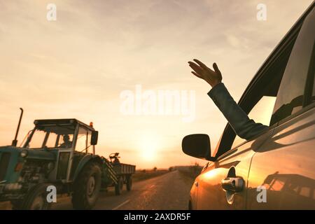 Sentire il vento mentre si guida attraverso la campagna, donna raggiungendo fuori mano dal finestrino in autunno il tramonto, il fuoco selettivo Foto Stock
