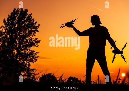 Piccolo Operatore Drone Sul Campo Fly Durante Il Tramonto Panoramico. Tecnologie Aeree. Foto Stock