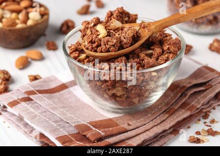 Muesli croccanti alla granola con miele naturale, cioccolato e noci in una ciotola di vetro su sfondo bianco, cibo sano, orientamento orizzontale Foto Stock