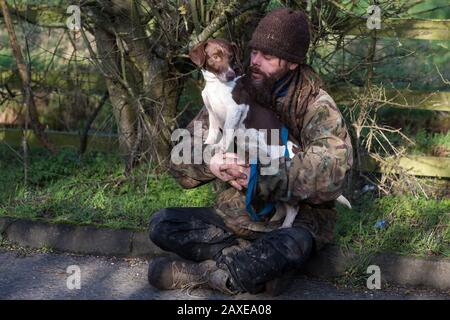 Denham, Regno Unito. 11 Febbraio 2020. Un attivista ambientale opposto a HS2 siede con un cane alla strada a Denham nella valle di Colne. I contraenti che lavorano per conto di HS2 stanno reinstradando i tralicci dell'elettricità attraverso un sito vicino Di importanza metropolitana per la conservazione della natura (SMI) insieme al collegamento ferroviario ad alta velocità. Credit: Mark Kerrison/Alamy Live News Foto Stock