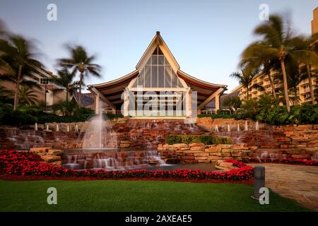 Hotel e resort in stile Bali in un ambiente tropicale con palme e una fontana all'entrata Foto Stock