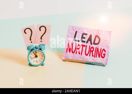 Testo Di Scrittura A Mano Mantenimento Dei Lead. Metodo concettuale della foto di costruire un rapporto con i clienti potenziali Orologio di allarme di formato mini accanto ad un shee di carta Foto Stock