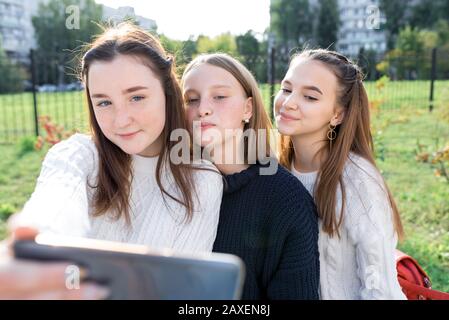 Tre adolescenti 12-14 anni, estate in città scattare foto al telefono, felice sorridendo posare. Social network Internet, applicazione guarda video Foto Stock