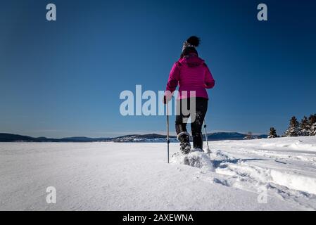 Donna di mezza età con racchette da neve in un soleggiato pomeriggio invernale. Foto Stock