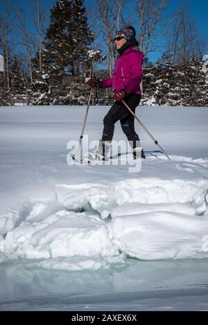 Donna di mezza età con racchette da neve in un soleggiato pomeriggio invernale. Foto Stock